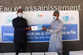 Mr. Mamadou DIA (right), Governor of the World Water Council representing President Loïc Fauchon, hands over a batch of soap to Mr. Serigne Mbaye Thiam, Senegalese Ministry of Water and Sanitation, during the ceremony on April 24, 2020.