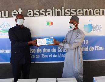 Mr. Mamadou DIA (right), Governor of the World Water Council representing President Loïc Fauchon, hands over a batch of soap to Mr. Serigne Mbaye Thiam, Senegalese Ministry of Water and Sanitation, during the ceremony on April 24, 2020.